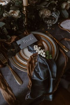 the table is set with gold and black plates, napkins, and silverware