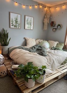 a bed made out of wooden pallets with plants on the bottom and lights above it