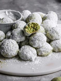 powdered sugar covered pastries on a white plate with a bowl of dipping sauce