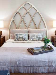 a white bed topped with pillows next to two lamps and a tray on top of it