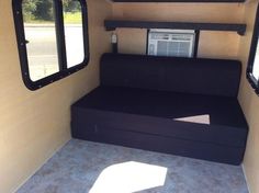 the inside of a trailer with two windows and a bed in it's corner