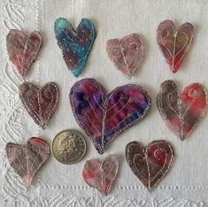 nine heart shaped glass magnets sitting on top of a white doily next to a penny