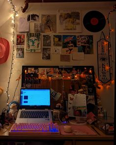 a laptop computer sitting on top of a wooden desk next to a wall covered in pictures