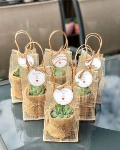 small bags filled with succulents sitting on top of a glass table covered in burlap