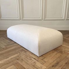 a large white ottoman sitting on top of a wooden floor