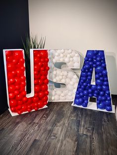 the letters are made out of balloons and plastic balls in red, white, and blue