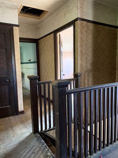 an empty room with wooden railings in the middle and doors open to another room