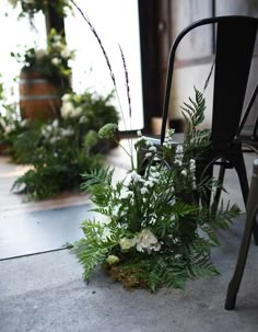 flowers and greenery on the ground next to a chair