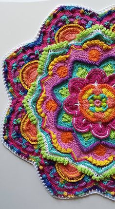 a crocheted doily is shown on a white surface with multicolored flowers