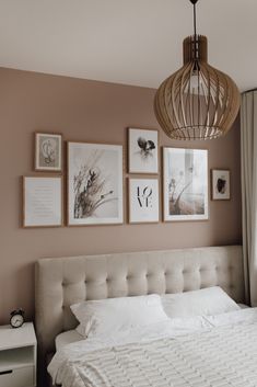 a bedroom with pictures on the wall and a white bed in front of a window