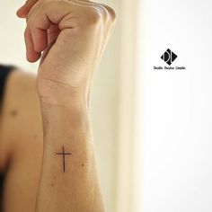 a woman's arm with a cross tattoo on it