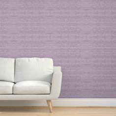 a white couch sitting in front of a purple wall