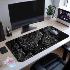 a computer desk with a black and white design on the mouse pad next to it