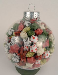 a glass ball ornament filled with lots of different types of buttons and bows