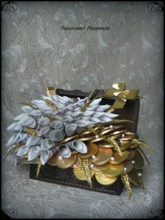 a suitcase filled with lots of gold and silver coins on top of a white wall