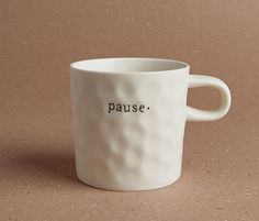 a white coffee cup with the word pause written on it