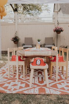 an outdoor table and chairs set up for a birthday party with balloons in the background