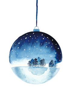 a blue ornament with trees and snow on the top, hanging from a string