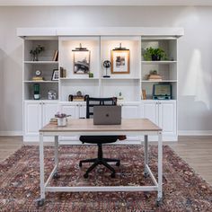 a desk with a laptop on top of it in front of some bookshelves