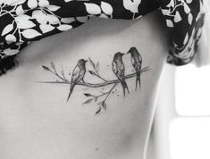 two birds sitting on a branch tattoo on the side of a woman's stomach