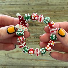 two hands are holding a bracelet made out of candy canes and christmas themed beads