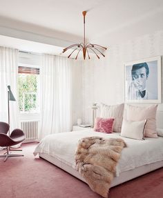 a bedroom with pink carpet, white walls and a chandelier hanging from the ceiling