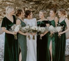 a group of women standing next to each other wearing green dresses and holding bouquets