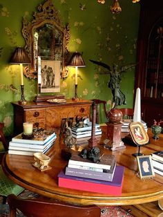 a table topped with lots of books on top of a wooden table next to a mirror