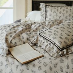 an open book laying on top of a bed next to pillows and pillowcases