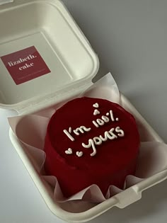 a red cake in a white box with writing on it