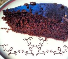 a piece of chocolate cake on a plate with blue icing and swirl designs around the edges