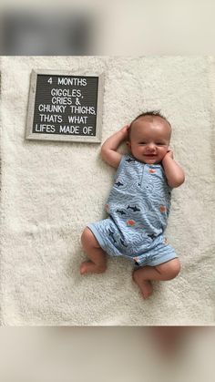 a baby laying on top of a blanket next to a sign