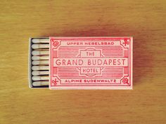 an unused matchbox for the grand budapest hotel sits on a wooden table with four matches in it