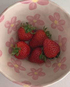 four strawberries in a pink and white bowl