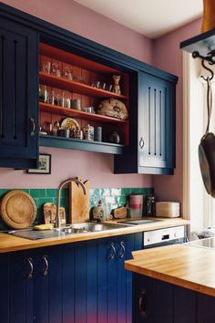 a kitchen with blue cabinets and wooden counter tops, along with an open shelf above the sink