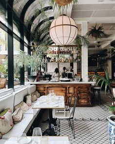 the interior of a restaurant with tables, chairs and potted plants hanging from the ceiling