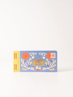 a blue and yellow box with an orange flower on the front, sitting on a white surface