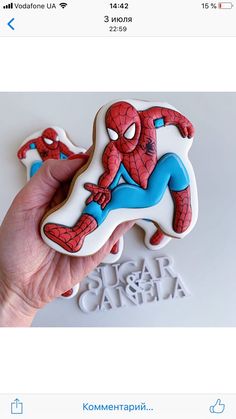 someone is holding up a spiderman cookie