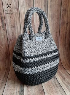 a black and white handbag sitting on top of a wooden floor next to a wall