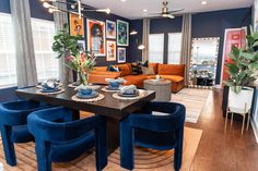 a dining room table with blue chairs and pictures on the wall in the living room