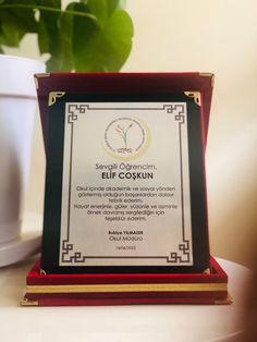 an award plaque sitting on top of a table next to a potted green plant