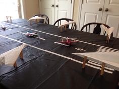 a table that has some paper airplanes on it, and two chairs at the end