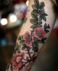 a woman's arm with flowers and leaves on it