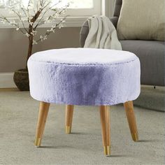 a round stool with wooden legs and a purple cover on it in front of a window