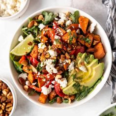 a white bowl filled with salad next to two bowls of rice and other food items