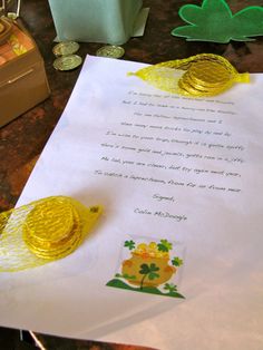 two yellow birds sitting on top of a piece of paper next to some gold coins