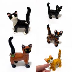 a hand is pointing at four different cat figurines on a white surface, each with an individual's finger