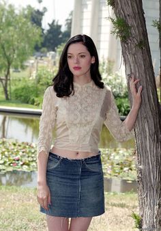 a woman standing next to a tree wearing a skirt