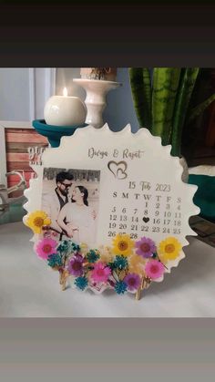 a wedding photo frame with flowers on the table next to a potted plant and vase