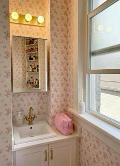 a bathroom with pink flowers on the walls and wall paper in the window sill